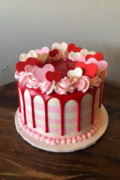 a decorated cake with hearts on top sitting on a wooden table next to a wall