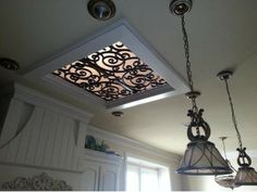 an ornate ceiling light fixture with two lights hanging from it's sides and a window in the background