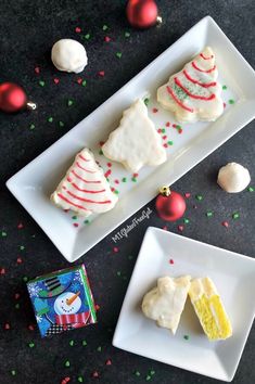 three pieces of christmas cake sitting on top of white plates next to candy and confetti