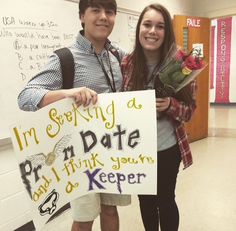 a young man and woman standing next to each other holding a sign