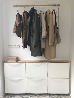 a coat rack with several coats hanging on it's hooks and two white drawers