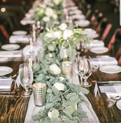 a long table with white flowers and greenery is set up for a formal dinner