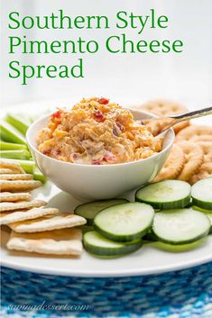 a white plate topped with cucumbers and crackers next to a bowl of dip