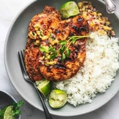 a plate with chicken, rice and vegetables on it next to a fork and knife