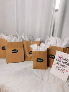 brown paper bags with black writing on them are sitting on a bed next to a sign