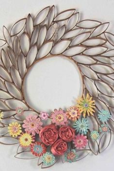 a metal wreath with flowers and leaves hanging on the wall in front of a white background