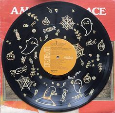 a record that has been decorated with halloween images and words on the side, sitting on a table