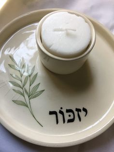 a small bowl on a plate with an inscription in hebrew