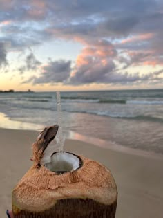 a coconut drink is being held up on the beach