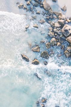 an aerial view of the ocean and rocks