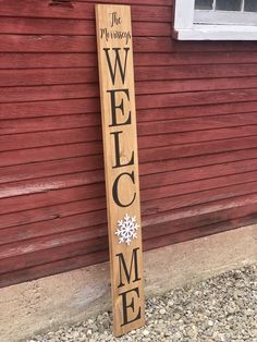 a wooden welcome sign sitting in front of a red building with snowflakes on it