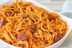 a bowl filled with noodles and bacon on top of a table