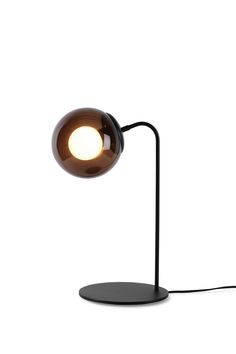 a black table lamp with an orange light on it's side and a white background