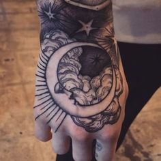 a person's hand with a tattoo on it and the moon in the sky