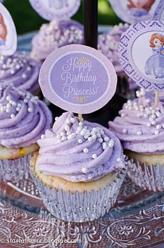 cupcakes with purple frosting and white sprinkles are on a glass plate