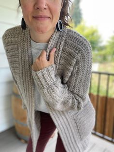 a woman wearing a gray sweater and black earrings