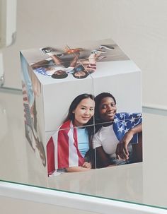 a photo cube with an american flag on it is sitting on a glass shelf in front of a white wall