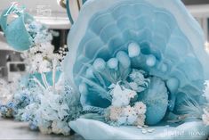 blue and white flowers are on display in front of a large sculpture with an intricate flower arrangement