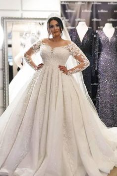 a woman in a wedding dress standing next to some dresses on mannequins