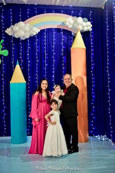 a family posing for a photo in front of a backdrop with balloons and lights on it