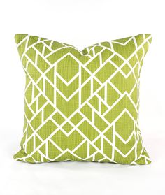 a green pillow with white geometric designs on it, sitting on a white tablecloth