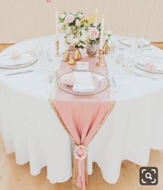 the table is set with plates, silverware and pink napkins for an elegant wedding reception