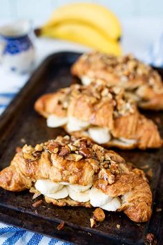 three pastries on a baking sheet with bananas in the background