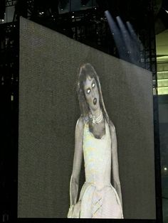 a woman in a white dress on a large screen