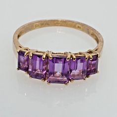 9ct Yellow Gold Ring with Purple Amethyst Gemstones (Size W) This exquisite 9ct yellow gold ring features a stunning purple amethyst gemstone, radiating elegance and charm. Features: Metal: 9ct Yellow GoldGemstones: 5 Purple AmethystsGemstone Sizes:Center Gem: 6.7mm x 4.7mmSide Gems: 5.9mm x 3.7mmEnd Gems: 4.6mm x 2.4mmHallmarks: Authenticated with hallmarks on the inside of the band (please see photos)UK Ring Size: WRing Diameter: 20.8mm (approximate)Ring Circumference: 65.3mm (approximate)Weig Yellow Gold Amethyst Ring, Gold Amethyst Ring, Ring Purple, Amethyst Gem, Yellow Gold Ring, Multi Stone Ring, Amethyst Gemstone, Amethyst Ring, Purple Amethyst