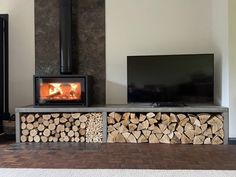 a fireplace with logs stacked in front of it and a flat screen tv on the wall