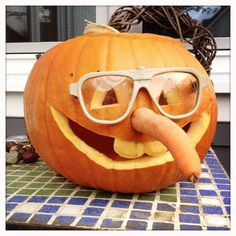 a pumpkin with glasses and a hot dog sticking out of it's mouth