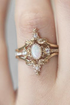 a close up of a person's hand wearing a ring with an opal stone