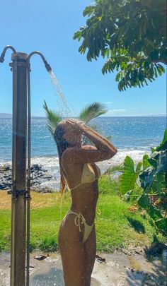 a woman in a bathing suit is spraying herself with water from a sprinkler