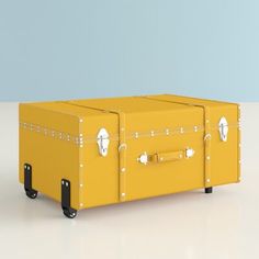 a yellow trunk sitting on top of a white table next to a blue wall and floor