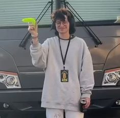 a person standing in front of a car holding up a frisbee and wearing headphones