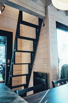 there is a black stair case in the corner of this room with wood paneling on the walls