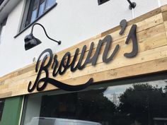 the outside of a restaurant with wood and metal lettering that reads roouu's