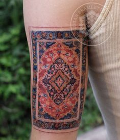 a woman's leg with a tattoo on it that has an old rug in the middle