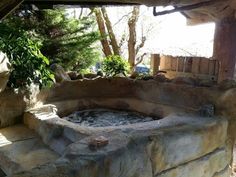 an outdoor hot tub in the middle of a patio with trees and rocks around it