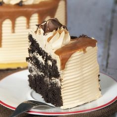 a slice of chocolate cake with white frosting on a plate next to a fork