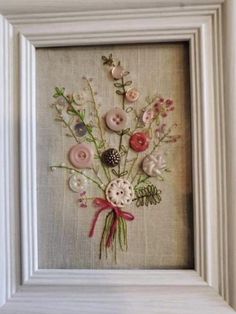 a white frame with buttons and flowers in it