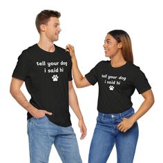 This 'Tell Your Dog I Said Hi Paw Print' Unisex Jersey Short Sleeve Tee gives off a fun and friendly vibe, perfect for dog lovers who just love all dogs. It can be worn casually or dressed up, making it versatile for everyday wear. Ideal for dog owners, animal lovers, and pet enthusiasts. Relevant for dog-themed holidays, pet birthdays, and casual outings. Product features - Made with 100% Airlume combed and ring-spun cotton, lightweight and breathable - Retail fit perfect for casual and semi-fo Relaxed Fit Short Sleeve Tops With Dog Print, Black Cotton Dog Print Top, Black Cotton Top With Dog Print, Dog Print Crew Neck Graphic Tee, Black Graphic Tee With Dog Print, Black Crew Neck T-shirt With Dog Print, Cotton Crew Neck Top With Dog Print, Funny Dog Print Crew Neck T-shirt, Dogs Paw Print