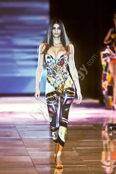 a woman walking down a runway wearing colorful clothing