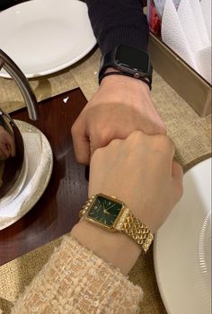 a person holding the hand of another person wearing a watch on their wrist at a table