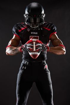 a football player holding a ball and wearing a black uniform with red accents on it