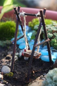 an old ladder is sitting in the dirt with blue rocks and moss growing on it