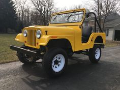 a yellow jeep is parked on the side of the road in front of a house