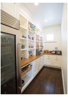 a kitchen with wooden floors and white cabinets, including an open refrigerator freezer door