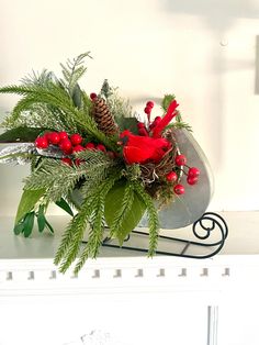 a vase filled with red flowers and greenery