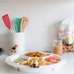 a white plate topped with chips and guacamole next to a bag of chips